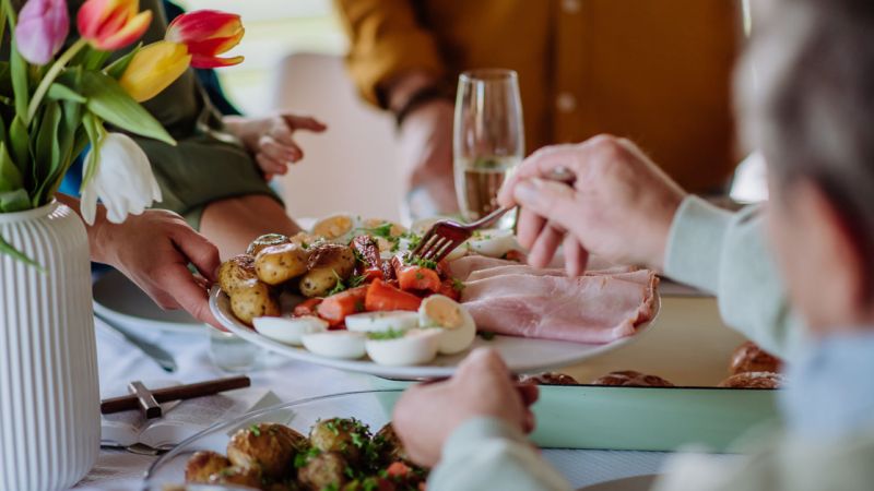 A family sits down at the table to enjoy an Easter feast together.