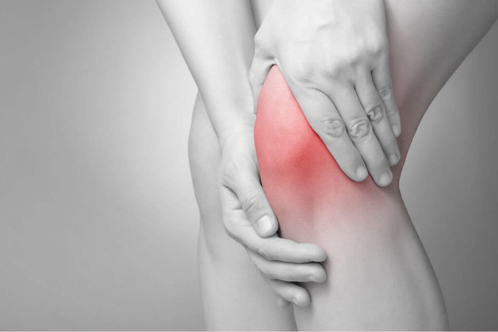 a woman grabbing her knee in pain from inflammation can use chicken bone broth to help. 