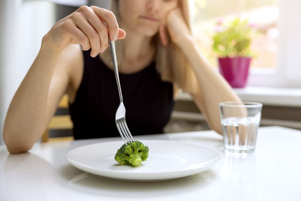 A woman picking at a broccoli but not eating it could use super greens powder instead. 