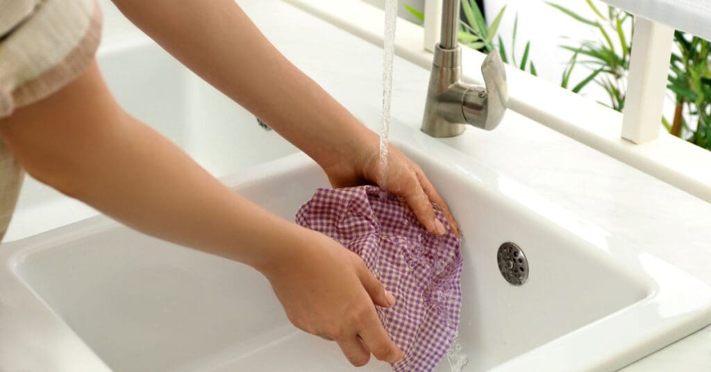 A woman washes a beeswax wrap with cold water and mild soap. 