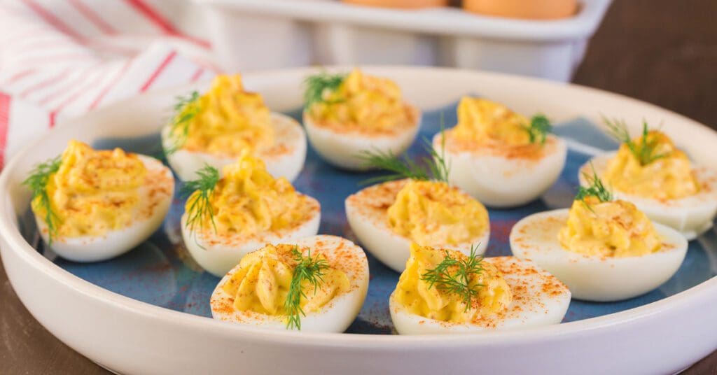 A dish of deviled eggs sits on a serving plate on a table as part of an Easter feast. 