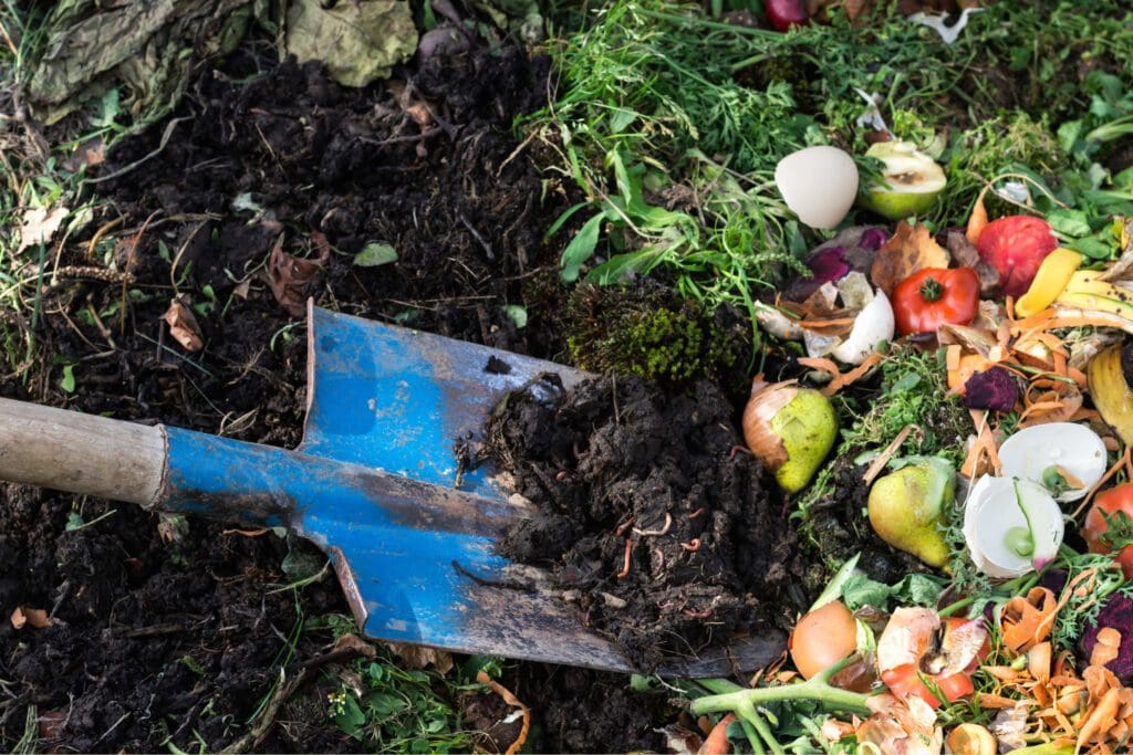 A person shovels a pile of fresh organic food scraps into a compost heap. Learning how to compost means knowing which materials make the best compost. 